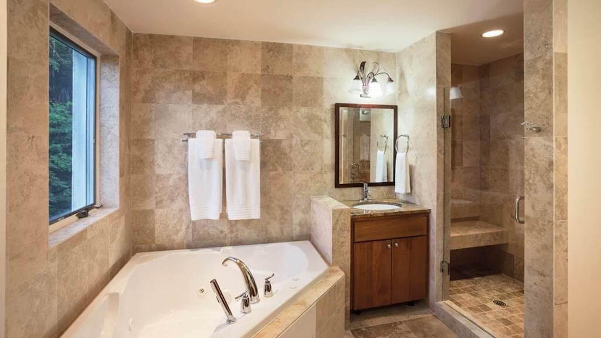 A bathroom with a large bathtub, a sink, a mirror, and a shower.