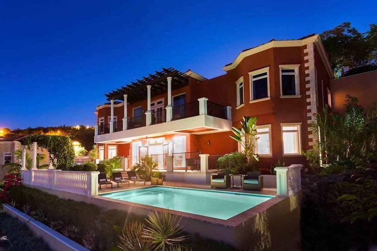 A two-story house with a swimming pool, outdoor seating, and a pergola.