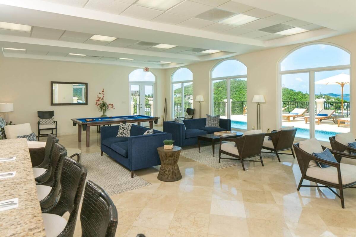 A spacious living area with a pool, comfortable seating, and large windows offering a view of the outdoors.