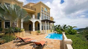 A large house with a swimming pool, outdoor seating, and tropical landscaping. - The Hills, St John (St. John)