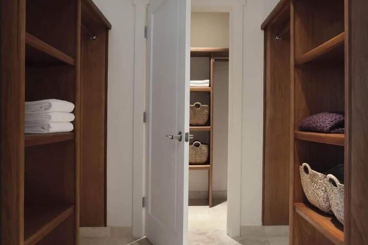 A hallway with wooden shelving units on either side, leading to a white door.