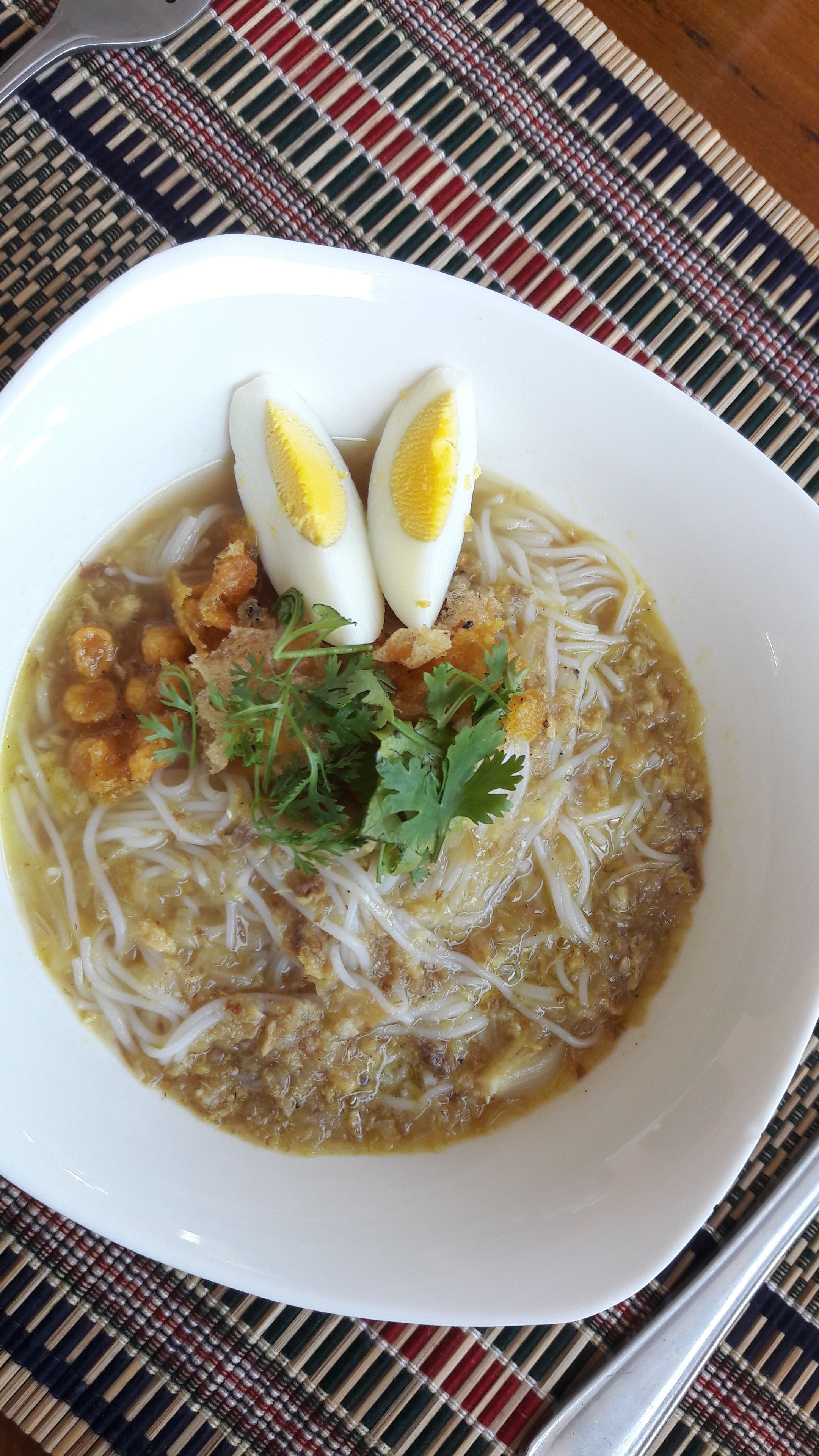 Un tazón de sopa de fideos con huevos cocidos y cilantro picado.