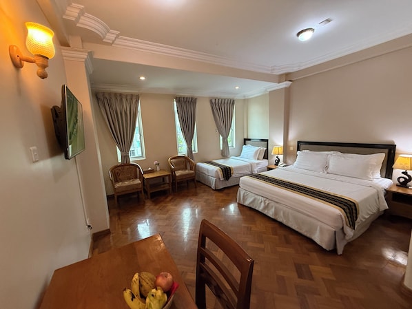 A hotel room with two beds, a dining table with fruit, and a TV. - Grand Laurel Hotel (Yangon)