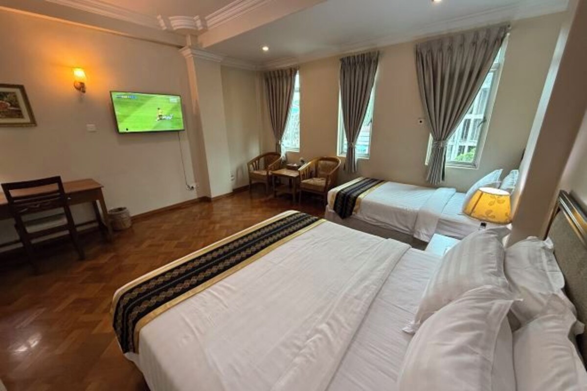 Habitación de hotel con dos camas, televisión, escritorio y una silla.