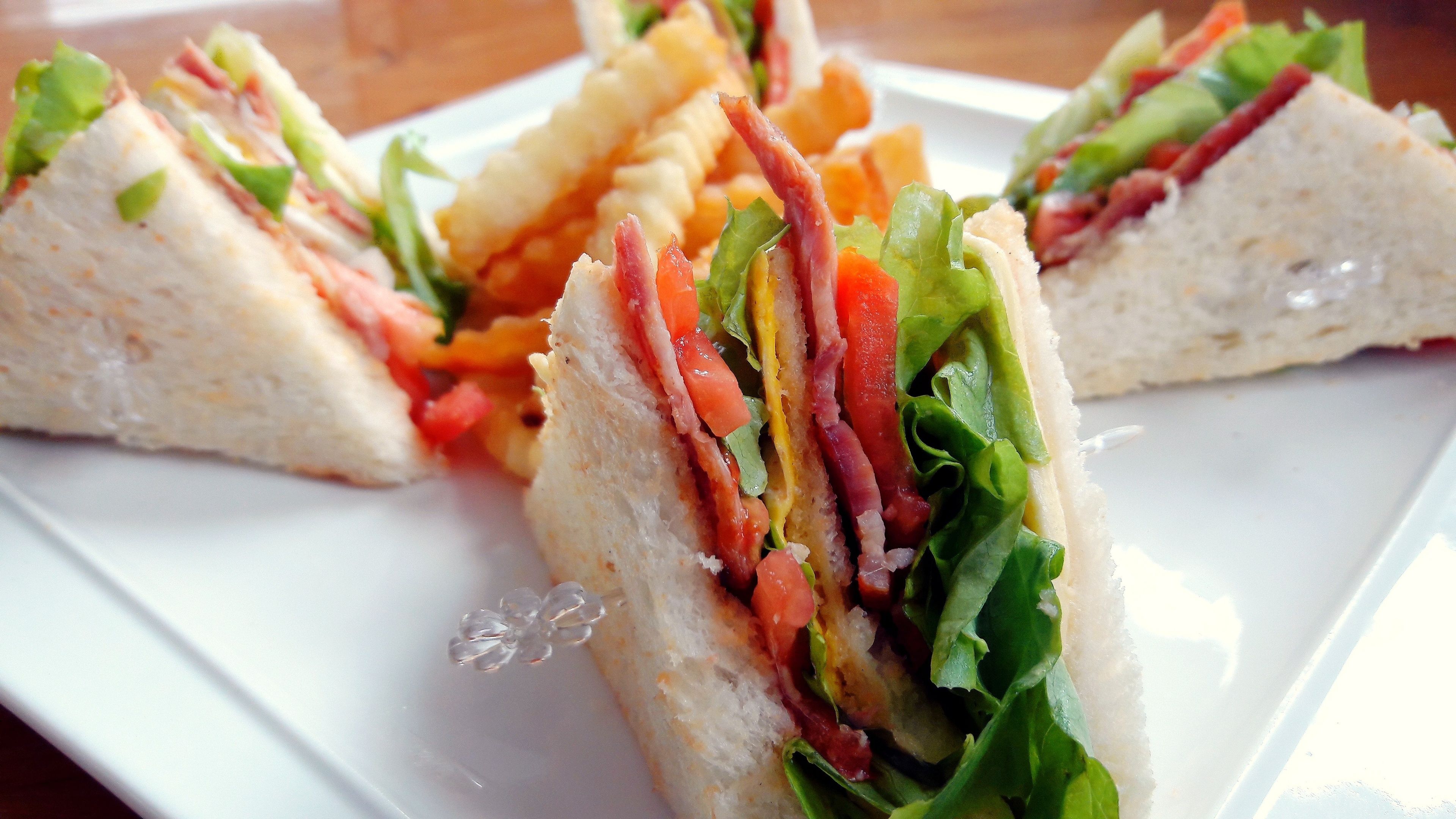 A sandwich cut into triangles, placed on a white plate.