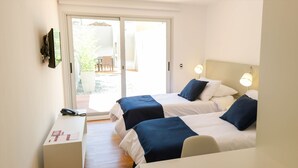 A hotel room with two beds, a desk, and a sliding glass door to an outdoor area. - Mérit Montevideo Apart & Suites (Montevideo)