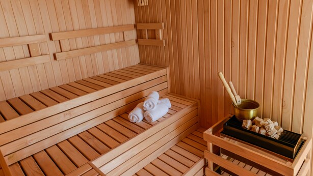 A wooden sauna with benches and a bench seat, a towel, and a heating element. - Mérit Montevideo Apart & Suites (Montevideo)