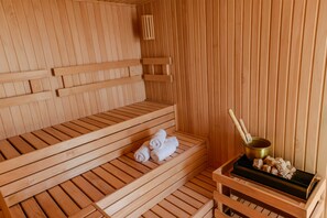 A wooden sauna with benches and a bench seat, a towel, and a heating element. - Mérit Montevideo Apart & Suites (Montevideo)