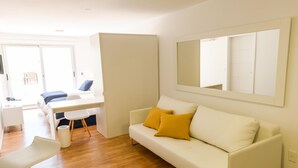 A modern living room with a white sofa, a dining table, and a large mirror on the wall. - Mérit Montevideo Apart & Suites (Montevideo)