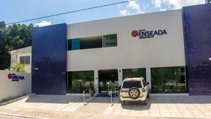 A hotel with a modern design, featuring a large glass facade and a parking area with a vehicle. - Hotel Enseada Aeroporto (Recife)