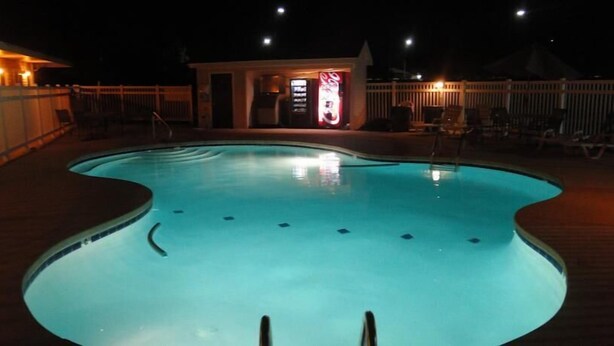 A swimming pool with a wooden deck and a Coca-Cola sign in the background. - Sea Esta Motel II (Millsboro)
