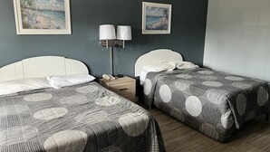 A hotel room with two beds, a nightstand with a lamp, and two framed pictures on the wall. - Sea Esta Motel II (Millsboro)