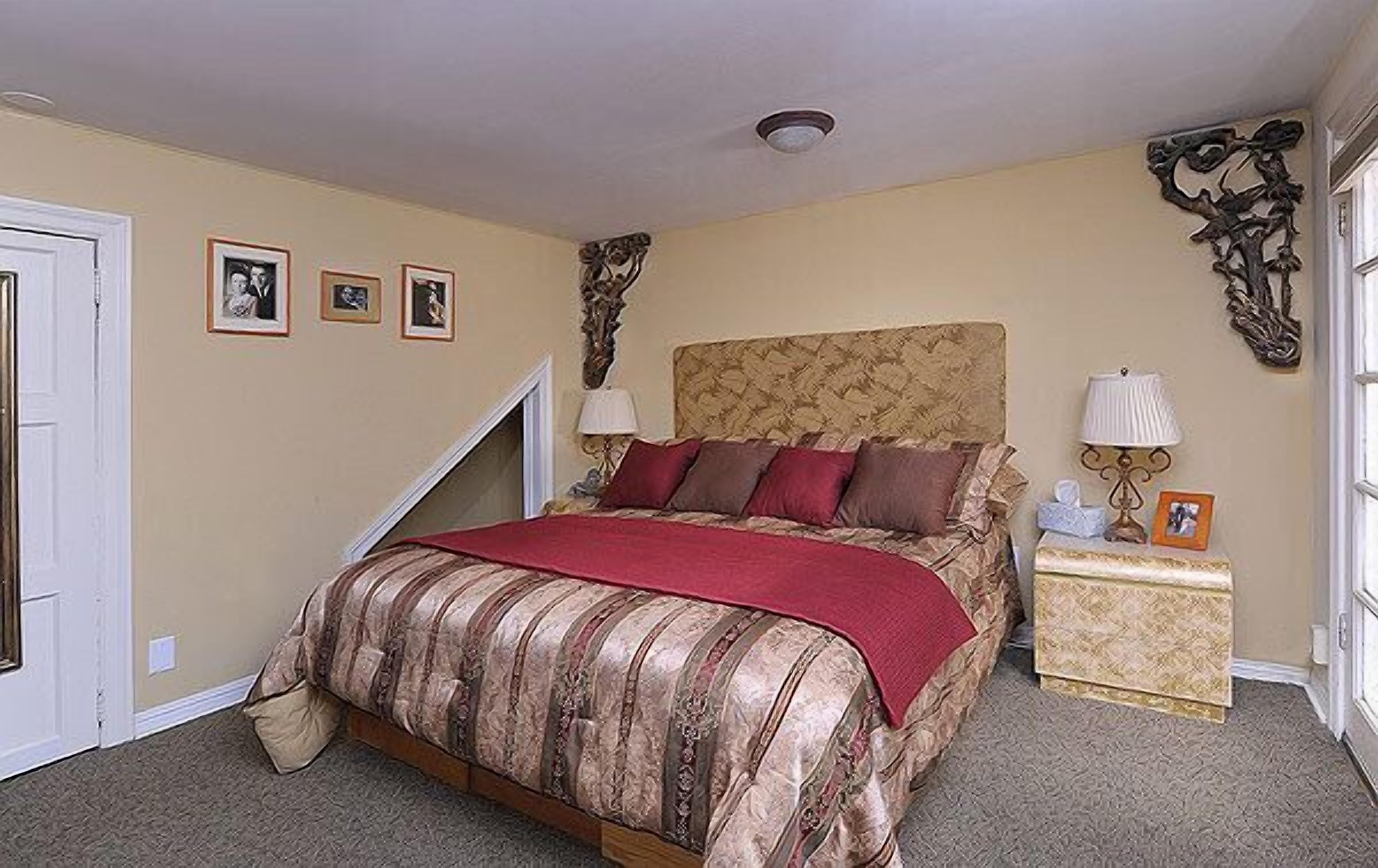 A bedroom with a bed, a nightstand, and a wall-mounted lamp.