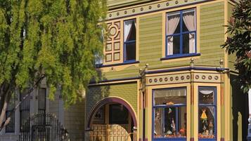 A Victorian-style building with ornate window frames, a bay window with decorative elements, and a small porch area.