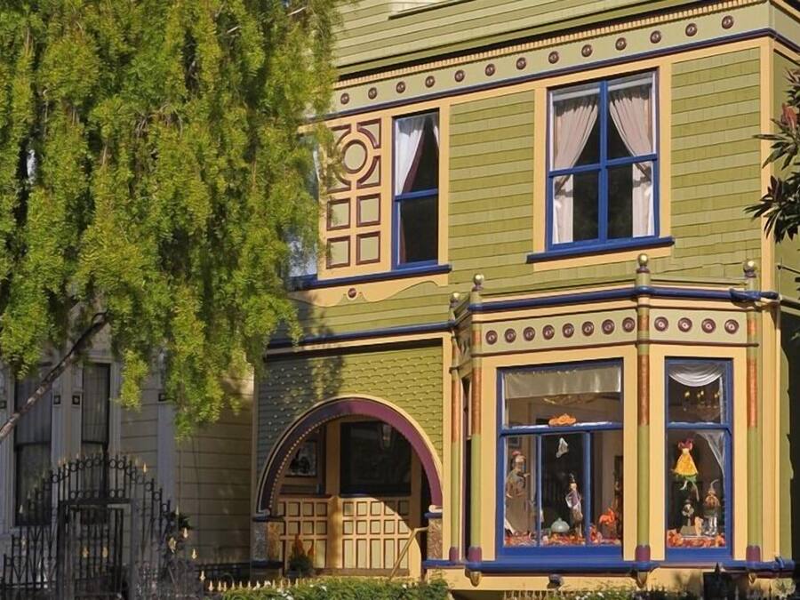 A Victorian-style building with ornate window frames, a bay window with decorative elements, and a small porch area.