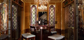 Uma sala de jantar com uma mesa redonda, cadeiras e janelas de vitrais.
