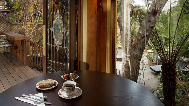 A wooden deck with a table set for two, featuring a plate of food and a cup of coffee.