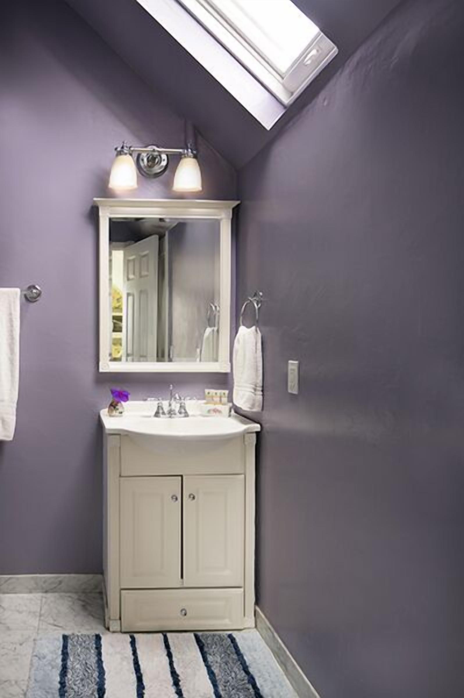 A bathroom with a white vanity, a mirror, and a towel rack.