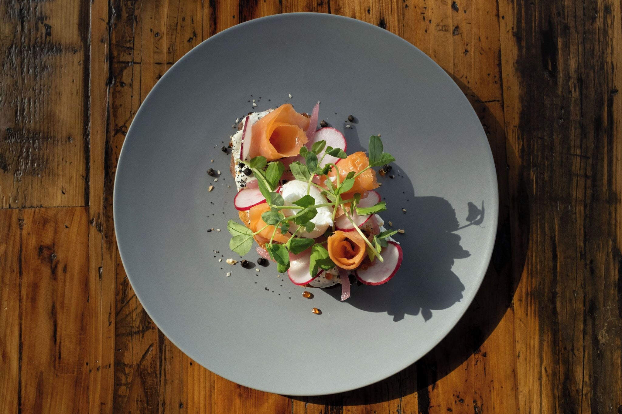 A round plate with a salad on a wooden table.