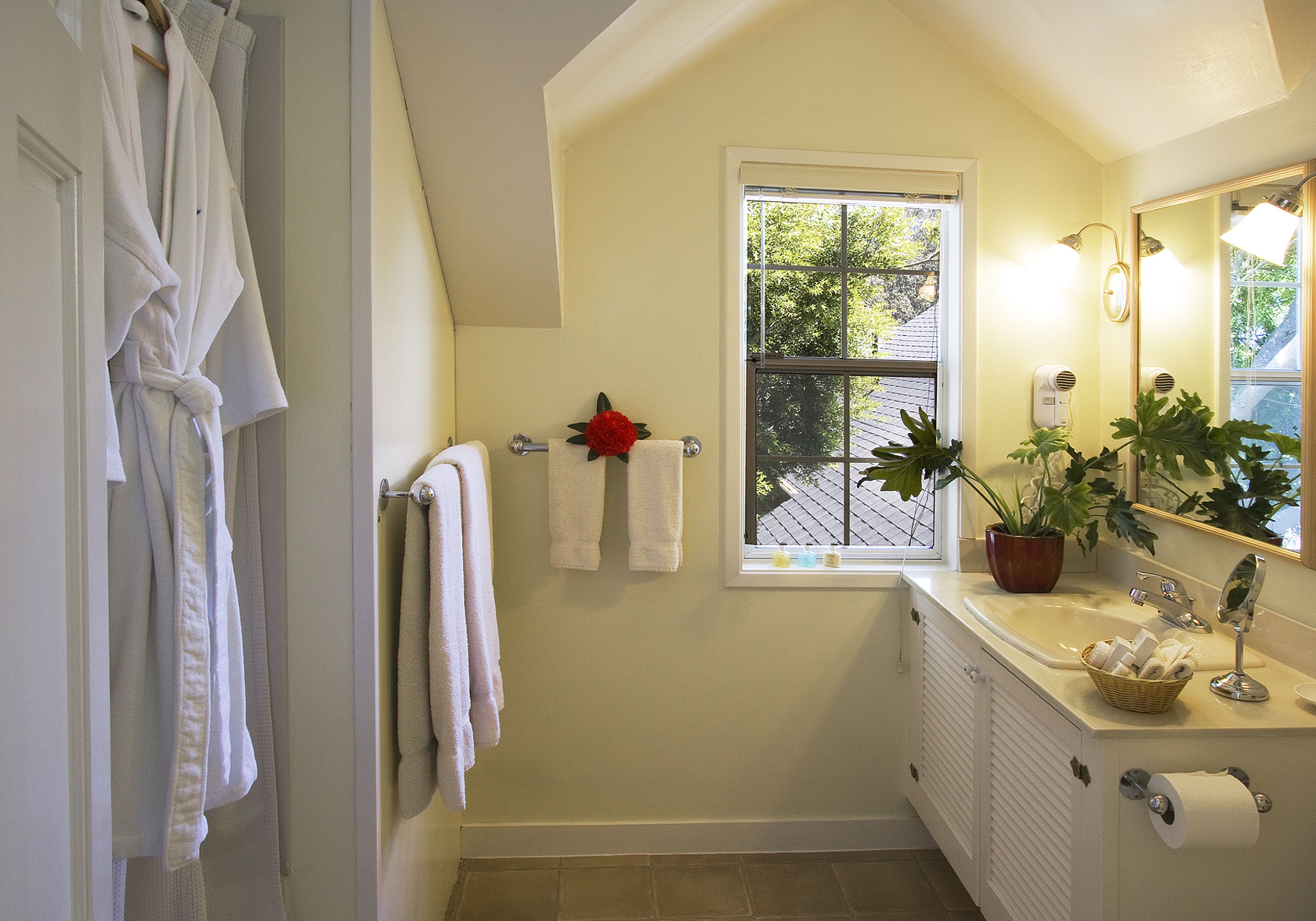 A bathroom with a window, a radiator, a sink with a mirror, and towels hanging on the wall.