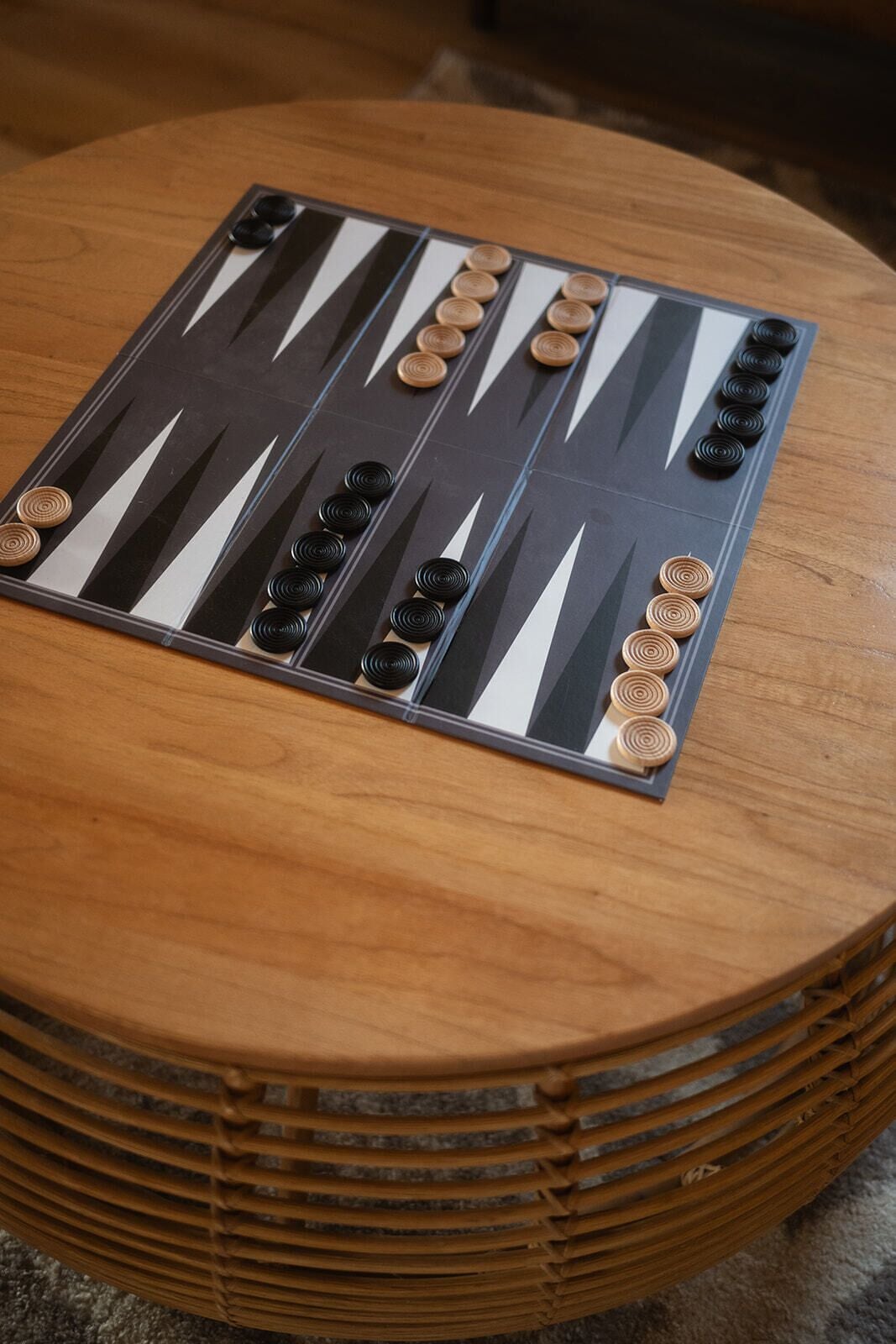 A backgammon board on a round wooden table.