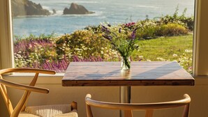 A table with a vase of flowers and a view of the ocean. - SCP Mendocino Coast Lodge  (Albion)