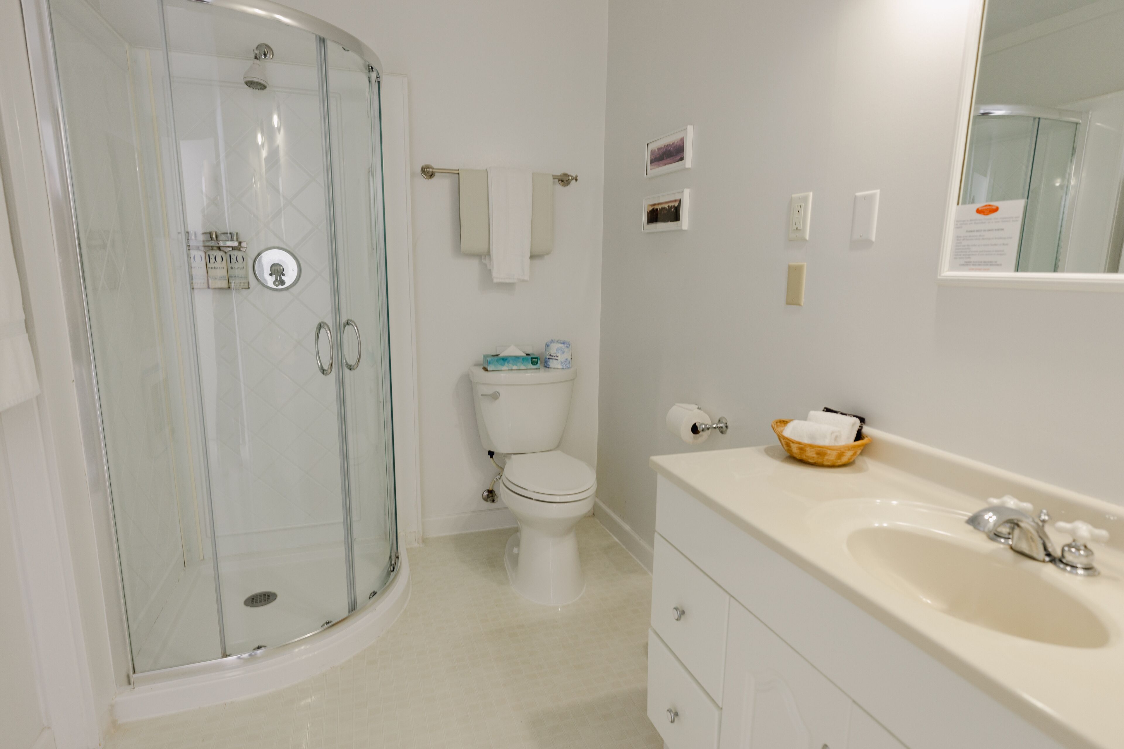 A bathroom with a glass-enclosed shower, a toilet, a sink with a mirror, and a towel rack.