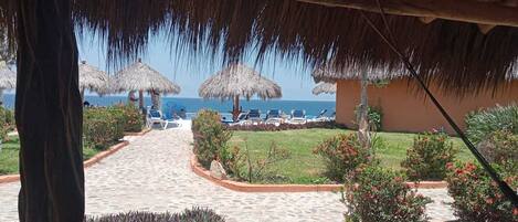 A beachside resort with thatched umbrellas, a paved walkway, and a view of the sea.
