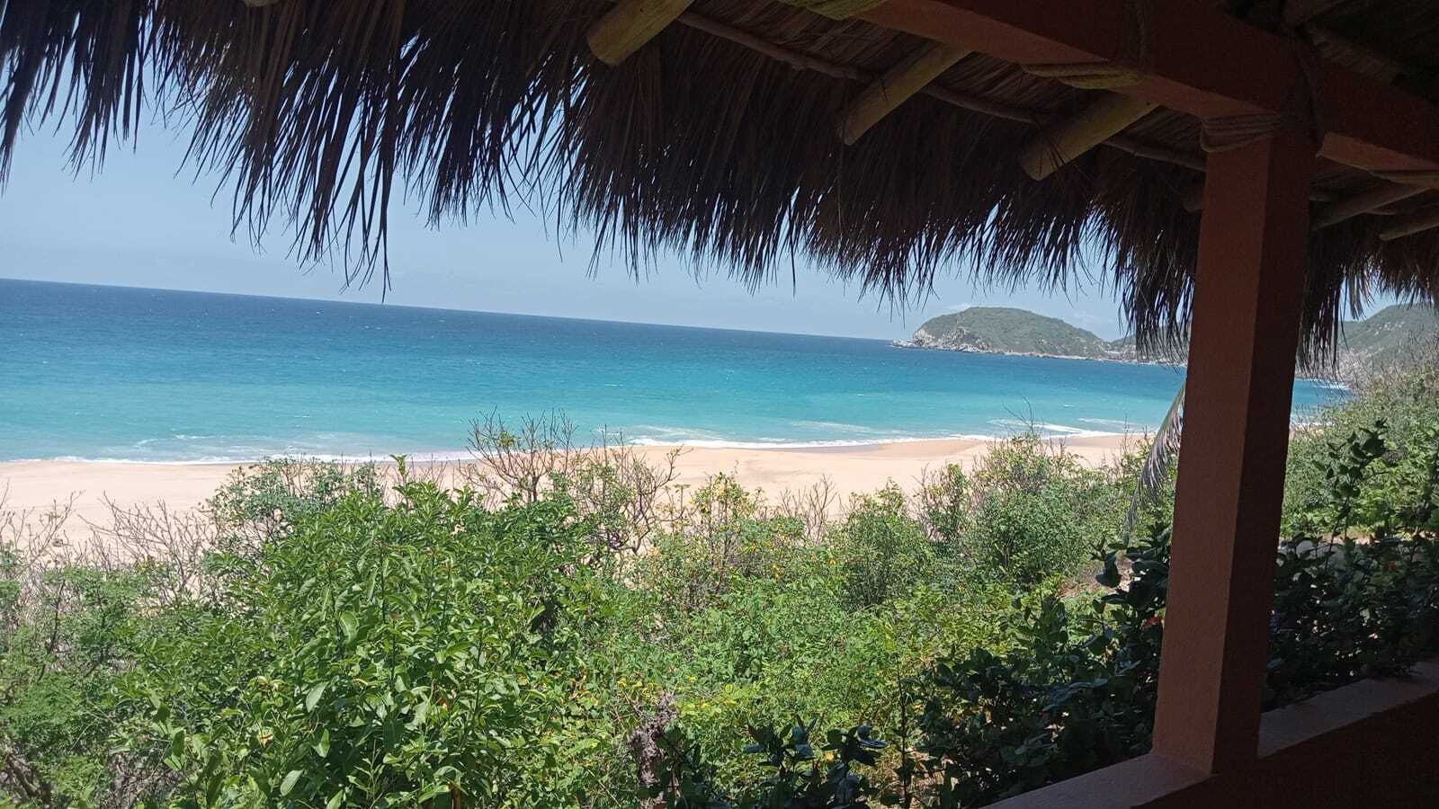 A beach view with a thatched roof structure.