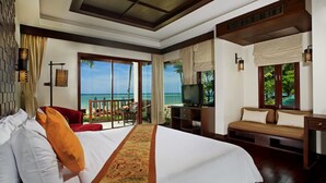 A hotel room with a large bed, a desk, a television, a sofa, and a balcony with a view of the ocean. - Khaolak Bay Front Resort (Takua Pa)