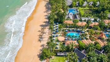 Relax by the beach and enjoy the resort's central pool surrounded by lush greenery and palm trees.