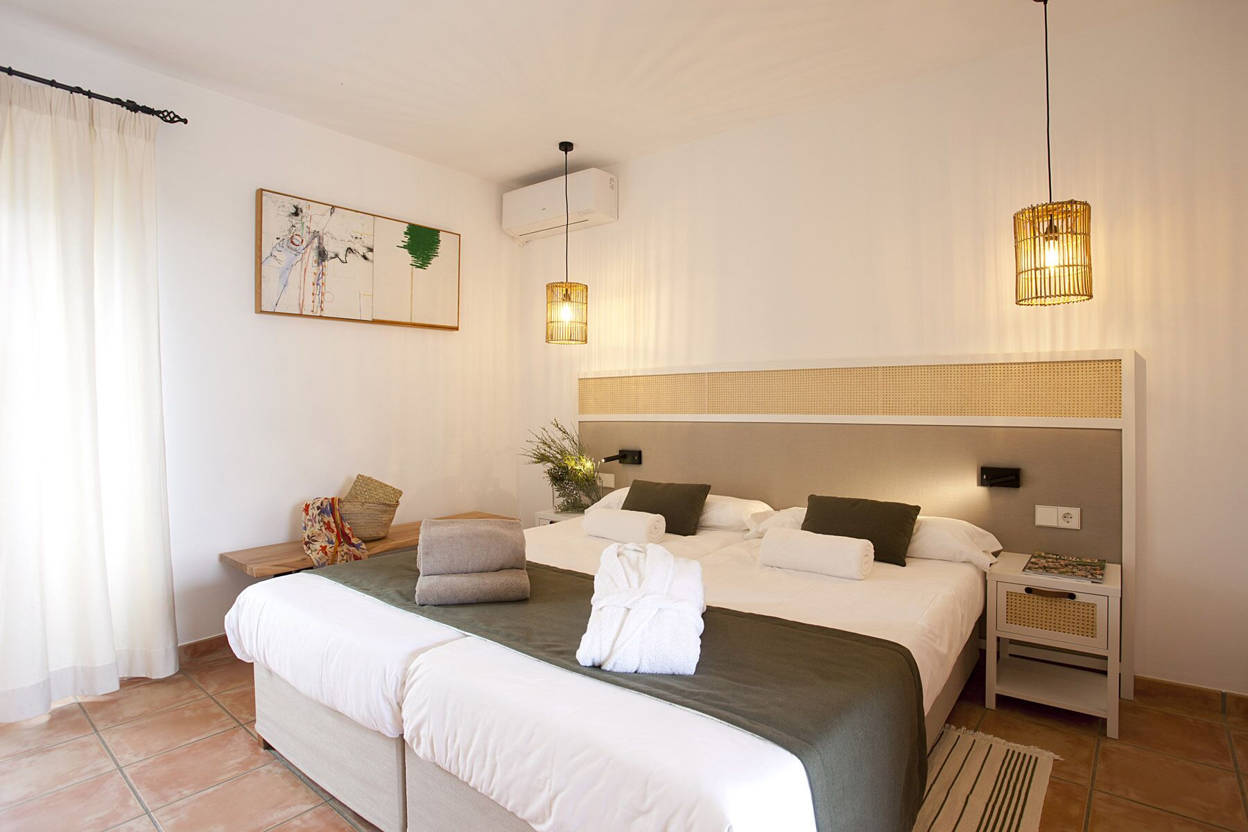 Een moderne slaapkamer met een groot bed, nachtkastjes, een wandairconditioner en een schilderij.