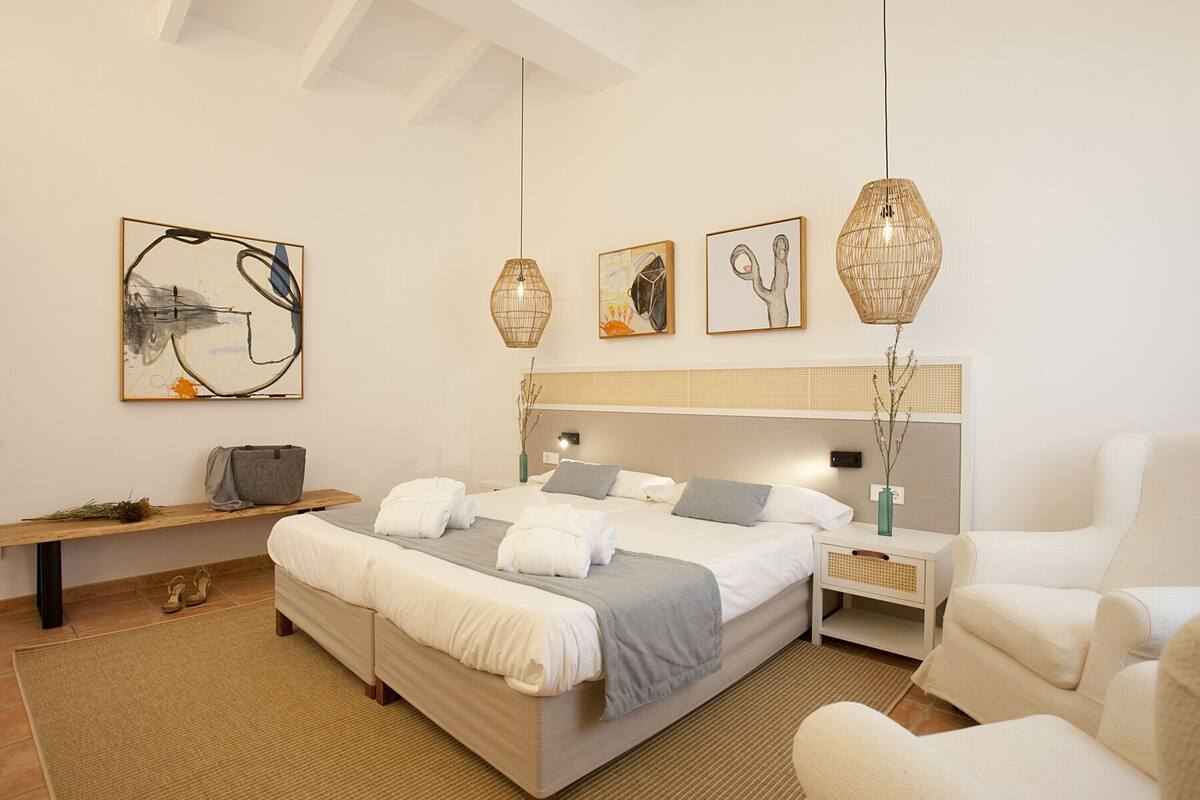 A modern bedroom with a large bed, bedside tables, a chair, and artwork on the walls.