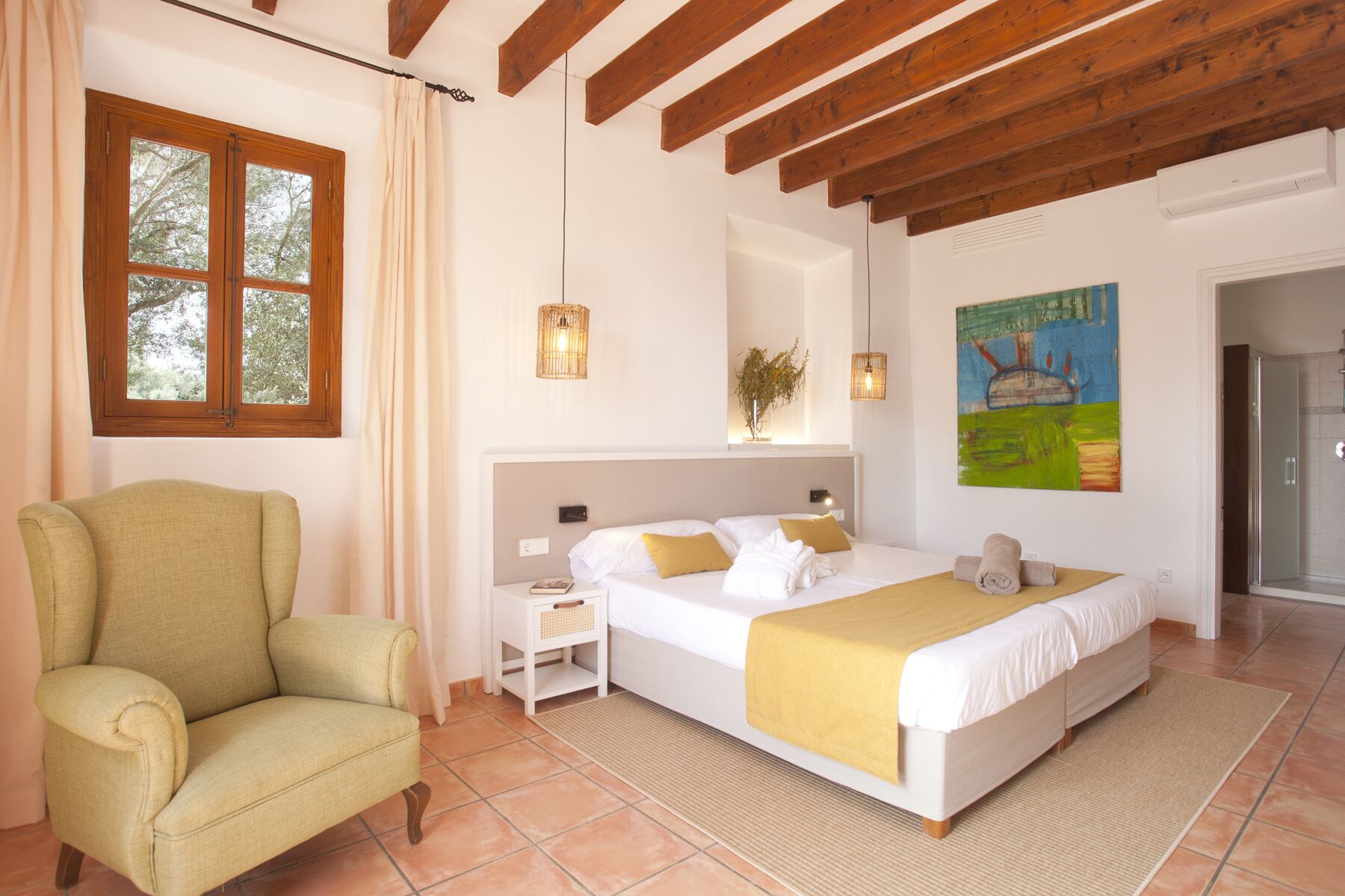 A bedroom with a bed, a chair, a nightstand, a lamp, and a painting on the wall.