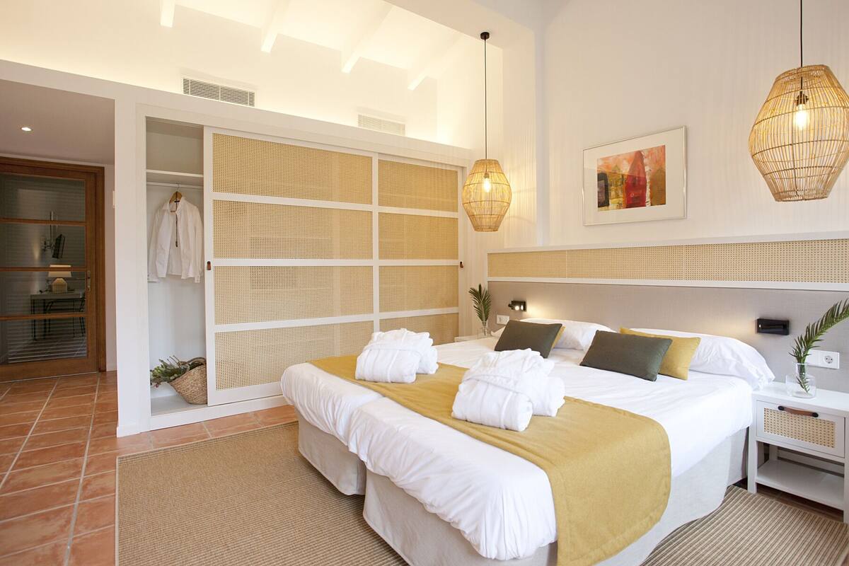 A modern hotel room with a large bed, a walk-in closet, and a large window.