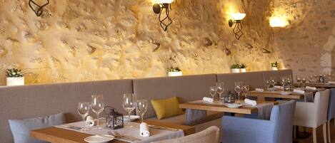 A restaurant with stone walls, wooden tables, and cushioned seating.