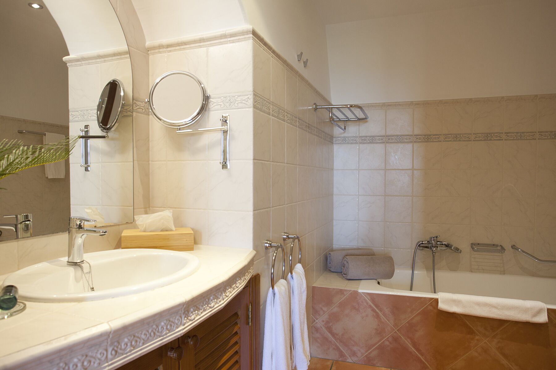 Un bagno moderno con un lavandino ampio, uno specchio e una vasca da bagno.
