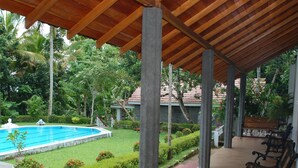 A covered outdoor area with a pool, benches, and lush greenery. - The Bungalow at Pantiya Estate (Matugama)