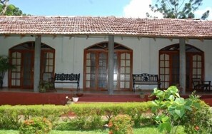 A building with a tiled roof, arched windows, and a covered porch with benches.