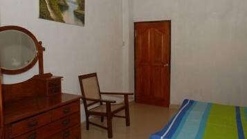 Un dormitorio con un aparador de madera, una silla, una cama con colcha a rayas y una puerta de madera.