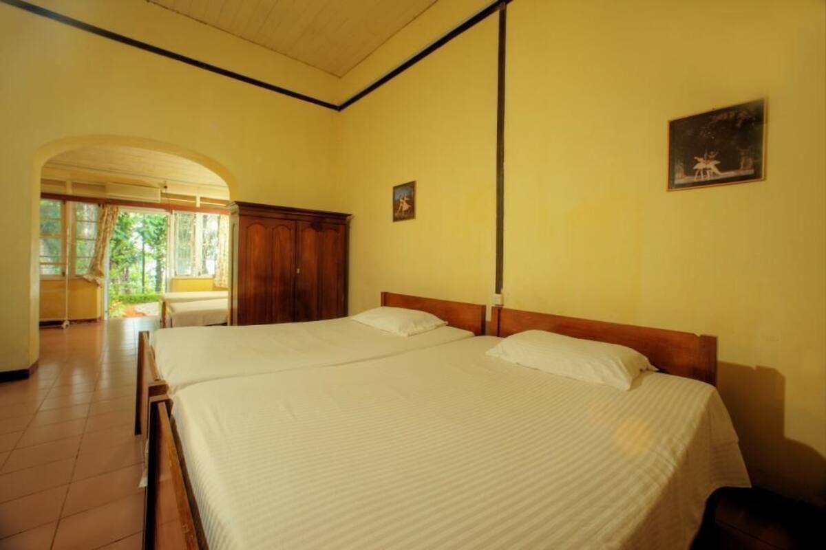 A hotel room with two beds, a wooden wardrobe, and a painting on the wall.