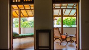 A room with a wooden ceiling, a green bed, a wooden chair, and a small table. - Villa Tara (Hikkaduwa)