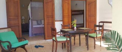 Un patio con una mesa redonda de madera, cuatro sillas, un sofá verde y una planta en maceta.