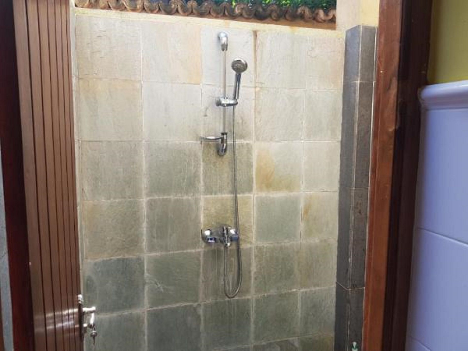 Un espace douche avec des murs carrelés et une porte.