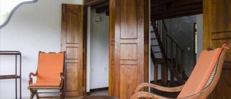 Une pièce avec une chaise en bois, une petite table ronde et un escalier menant à un autre niveau.