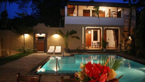 A two-story house with a swimming pool, outdoor seating, and a well-lit entrance. - Villa Tara (Hikkaduwa)