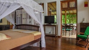 A room with a bed, a television, and a green chair. - Villa Tara (Hikkaduwa)