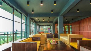A spacious indoor seating area with high ceilings, large windows, and a view of the outside. - Oak Ray Tea Bush (Kotmale)