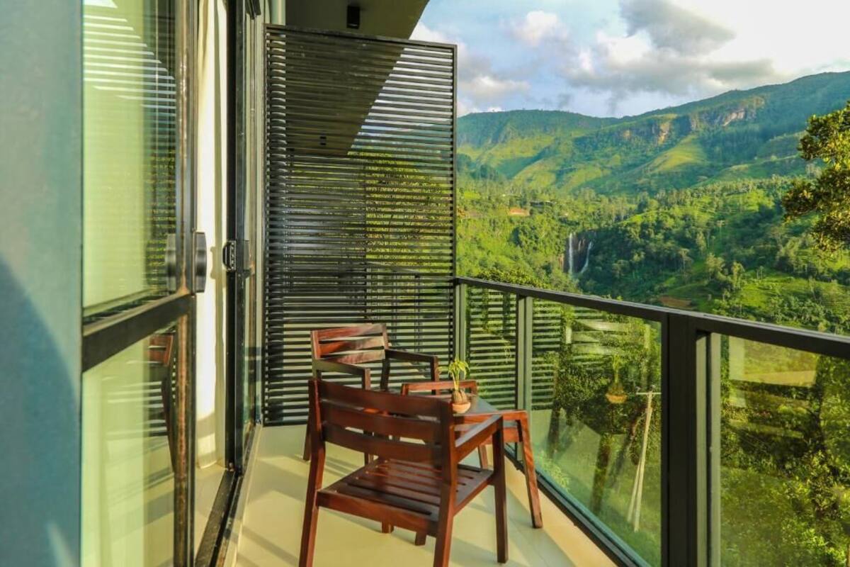 Ein Balkon mit Tisch und Stühlen, mit Blick auf eine gebirgige Landschaft.
