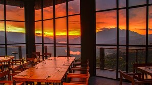 A restaurant with large windows offering a view of mountains and a sunset. - Oak Ray Tea Bush (Kotmale)